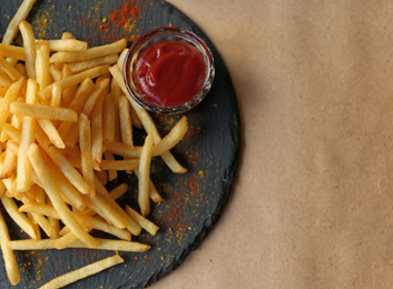 Photo of Tasty French fries with red sauce served on table in cafe, top view. Space for text