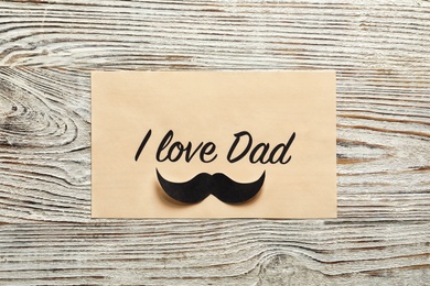 Photo of Card with words I LOVE DAD on wooden background, top view. Father's day celebration