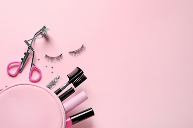 Photo of Flat lay composition with false eyelashes and makeup bag on pink background, space for text