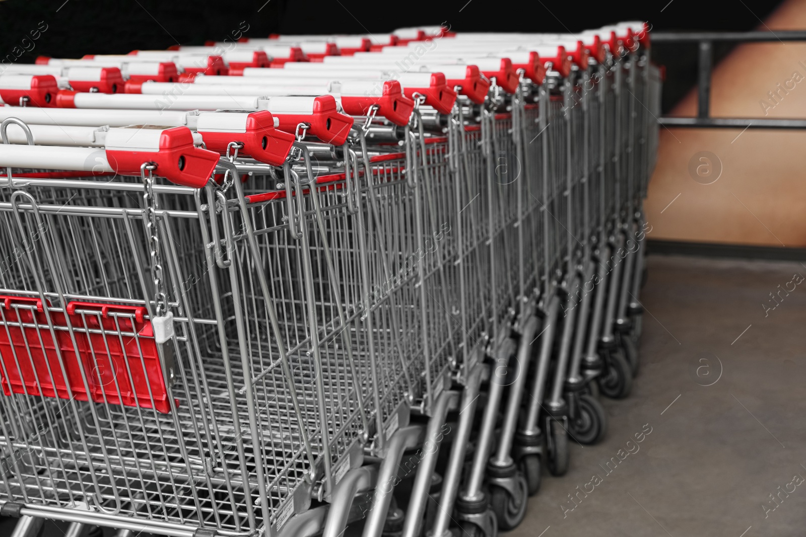 Photo of Many empty metal shopping carts near supermarket outdoors, space for text