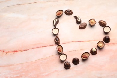 Photo of Heart made with delicious chocolate candies on marble table, top view. Space for text