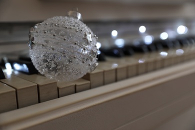 Beautiful bauble on piano keys, space for text Christmas music