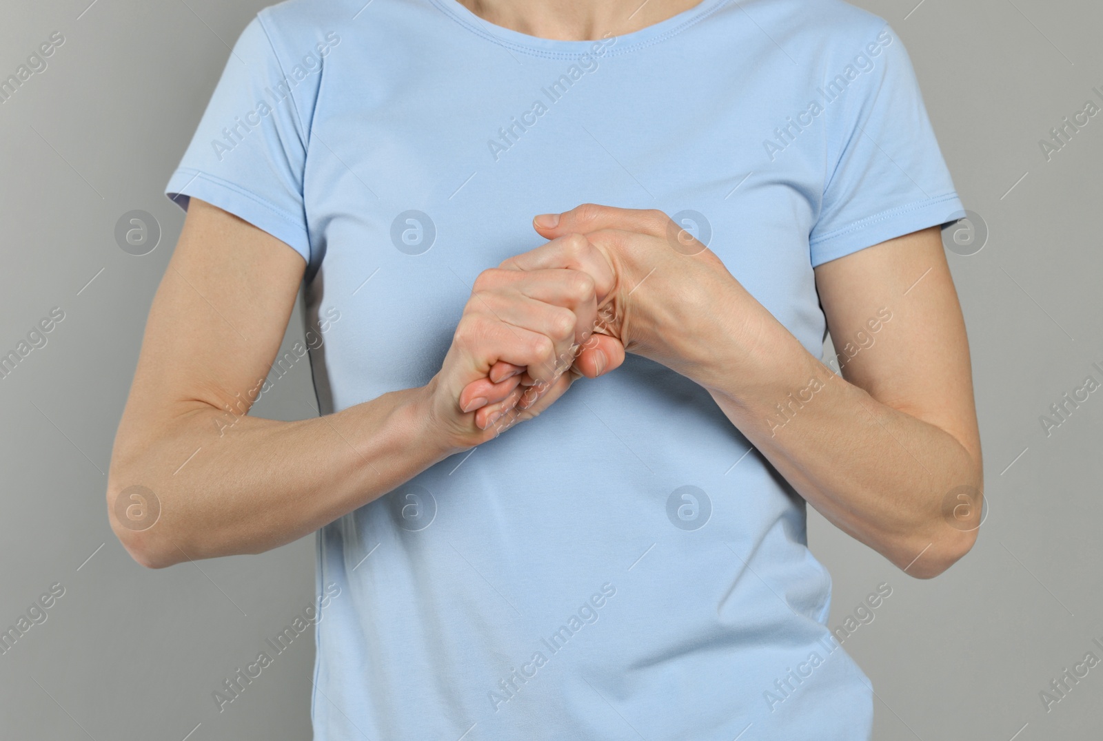 Photo of Woman cracking her knuckles on light grey background, closeup. Bad habit