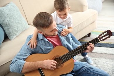Photo of Father playing guitar for his son at home