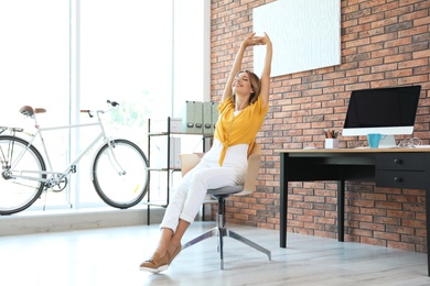 Photo of Beautiful young businesswoman stretching in office. Workplace fitness