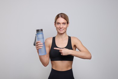 Photo of Sportswoman with bottle of water on light grey background