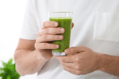 Photo of Man holding glass of delicious smoothie indoors, closeup