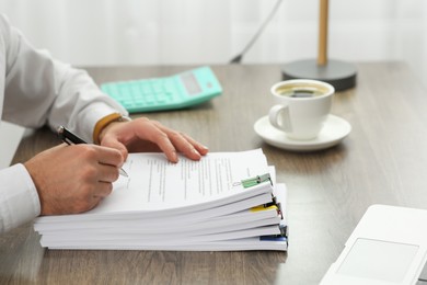 Photo of Man working with documents at wooden table in office, closeup