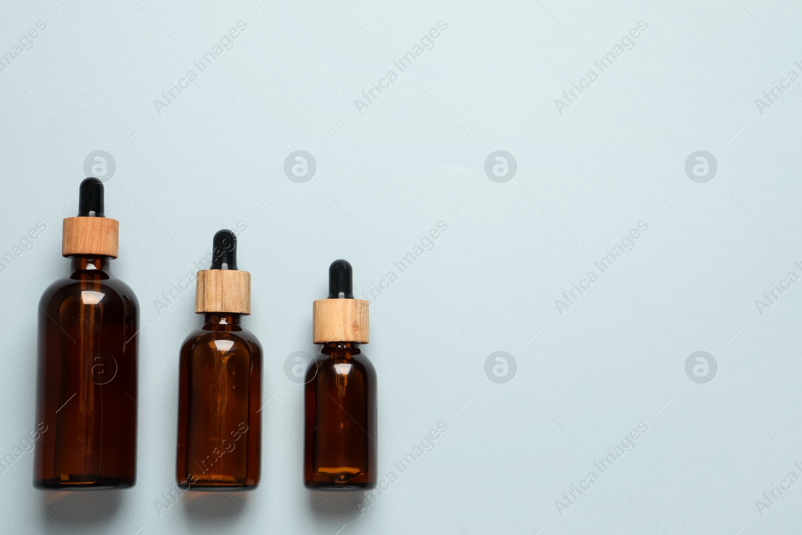 Photo of Bottles of face serum on light grey background, flat lay. Space for text