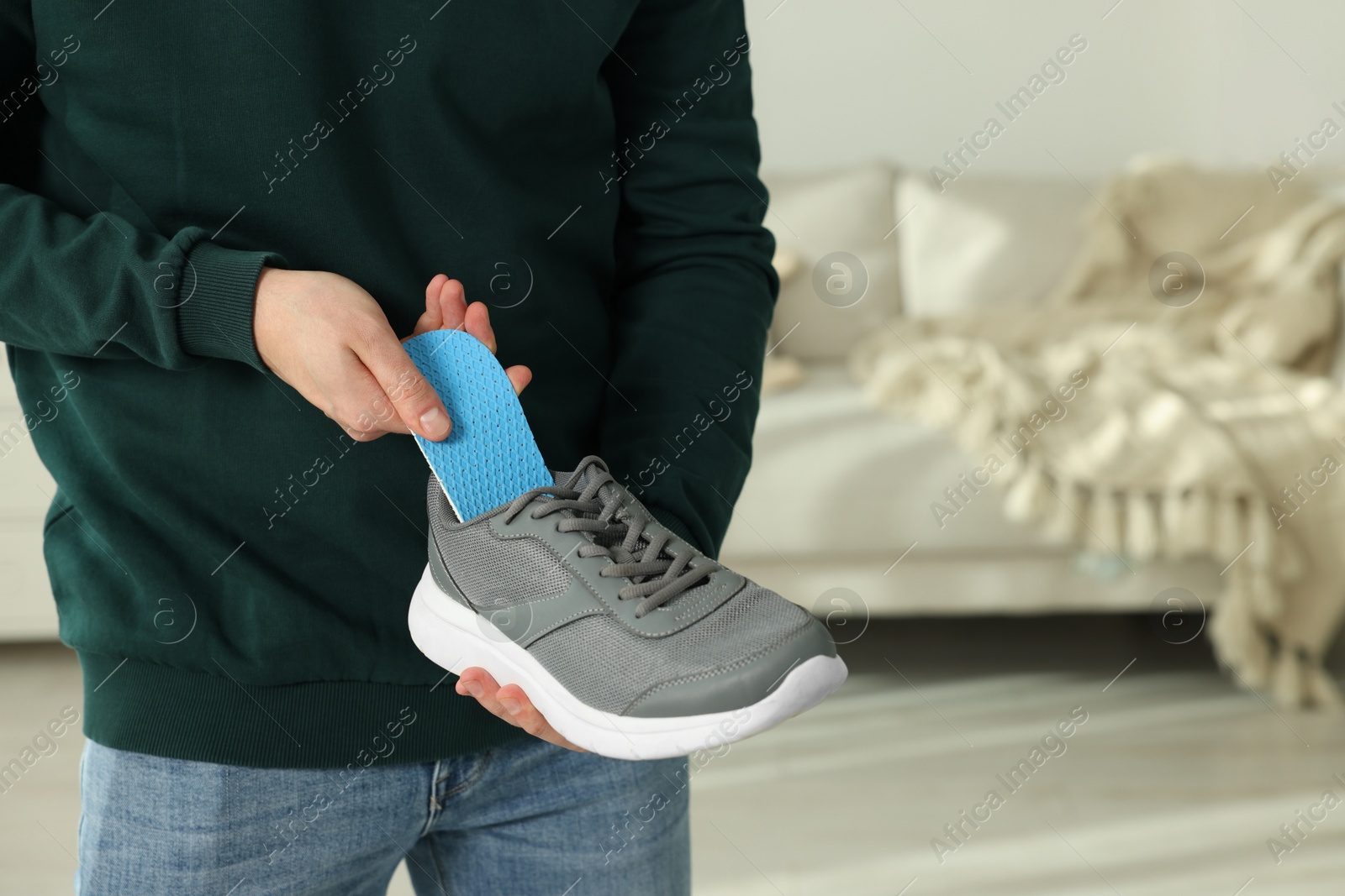 Photo of Man putting orthopedic insole into shoe indoors, closeup. Space for text