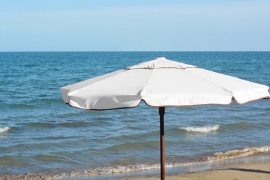 Photo of Beautiful white beach umbrella near sea on sunny day