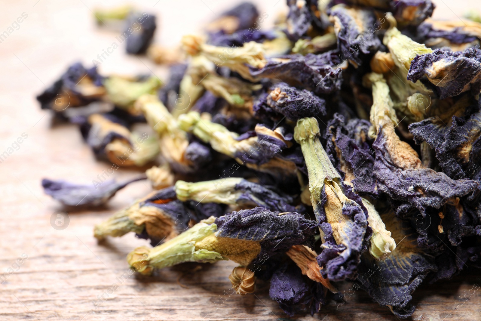 Photo of Pile of dry organic blue Anchan on wooden table, closeup. Herbal tea