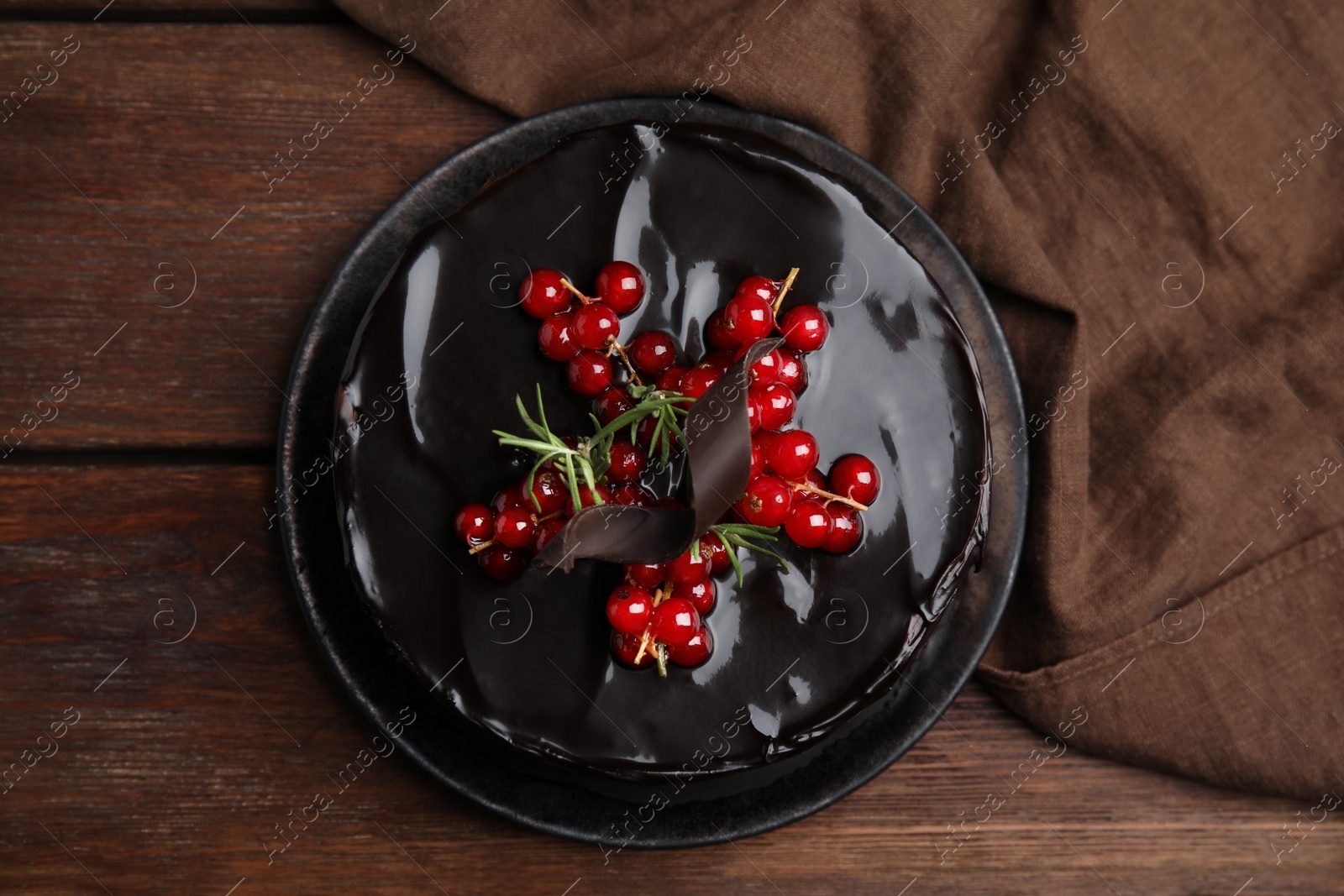 Photo of Tasty homemade chocolate cake with berries and rosemary on wooden table, flat lay