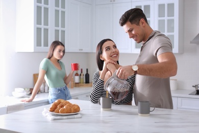 Unhappy woman feeling jealous, focus on couple spending time together in kitchen