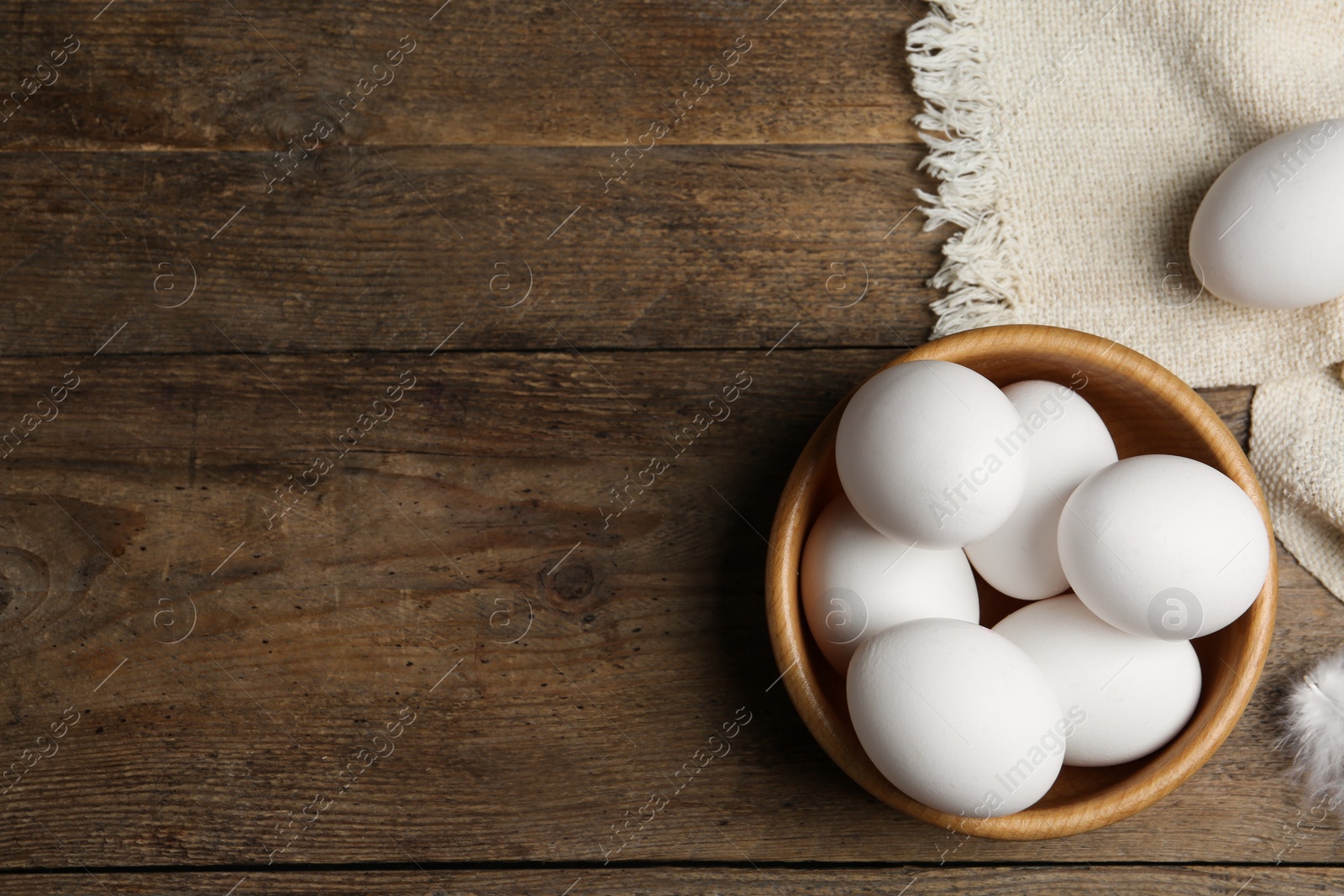 Photo of Many fresh raw chicken eggs in bowl on wooden table, flat lay. Space for text