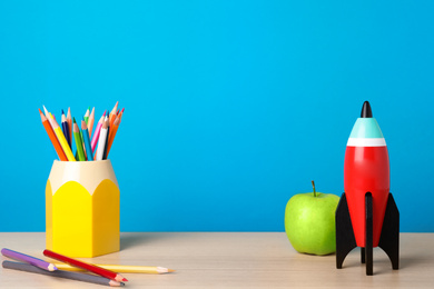 Bright toy rocket and school supplies on wooden desk. Space for text