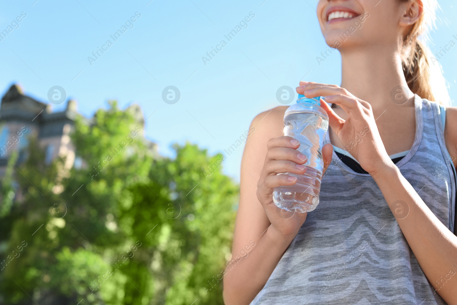 Photo of Young woman holding bottle with clean water on street. Space for text