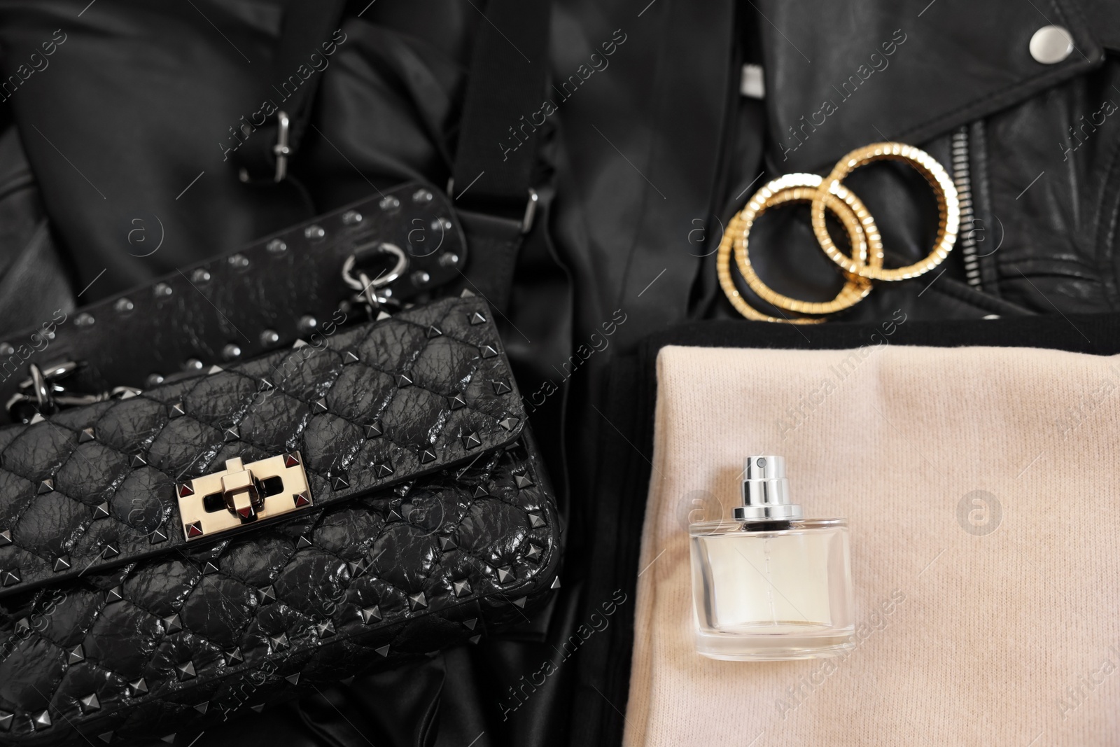 Photo of Folded clothes, bracelets, bottle of perfume, bag and black leather jacket , flat lay