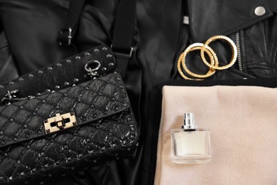 Folded clothes, bracelets, bottle of perfume, bag and black leather jacket , flat lay