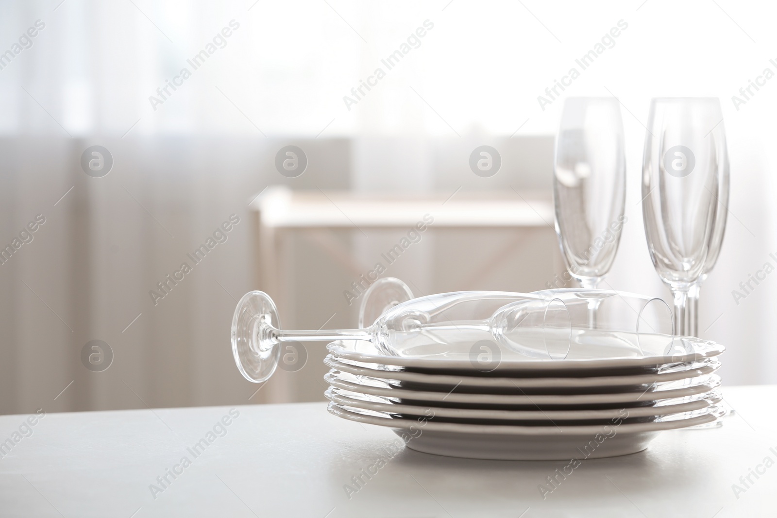 Photo of Set of clean dishware and champagne glasses on table indoors. Space for text