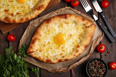 Fresh delicious Adjarian khachapuris served on wooden table, flat lay