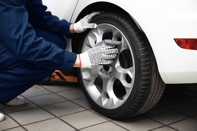 Photo of Mechanic cleaning wheel at tire service, closeup
