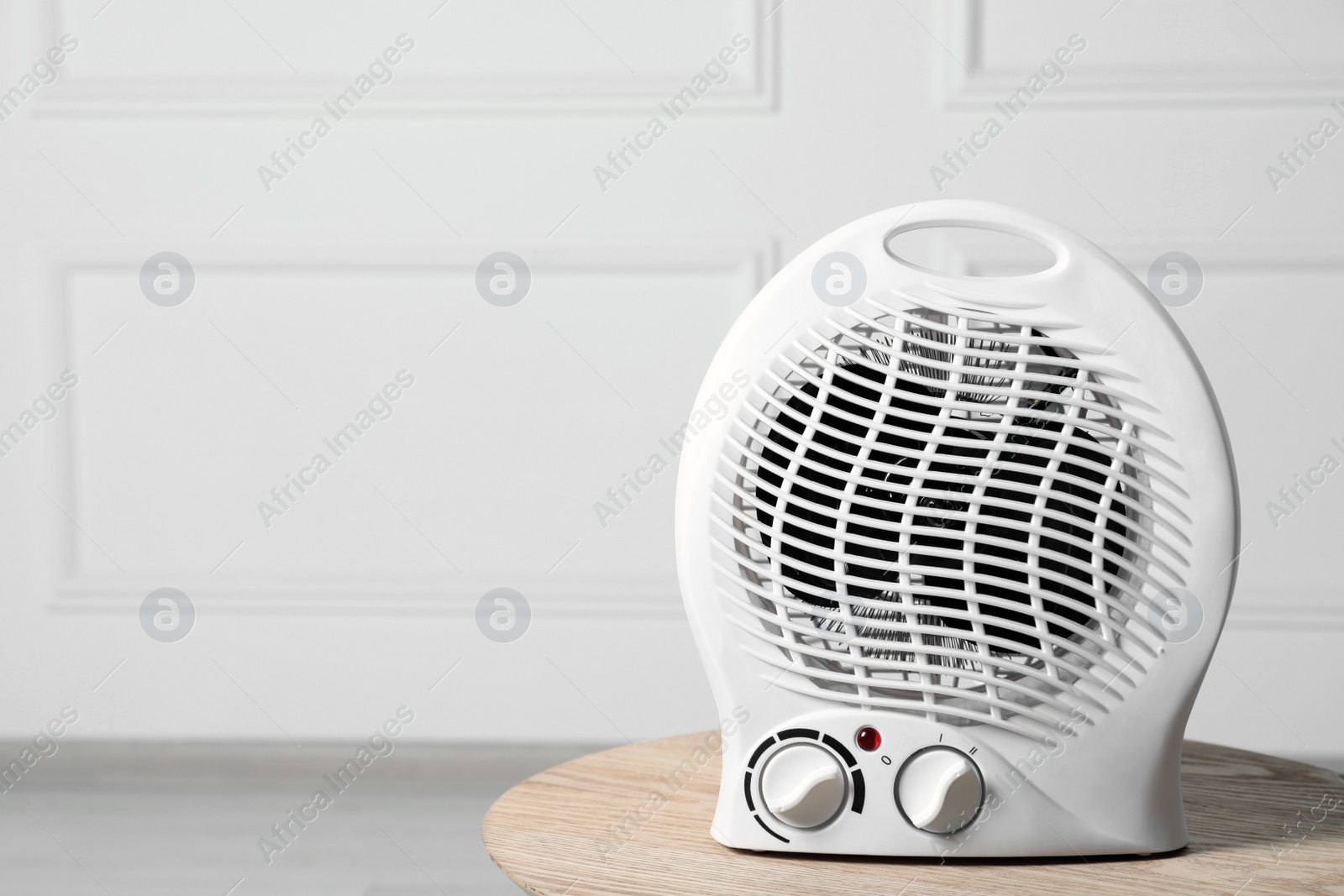 Photo of Modern electric fan heater on wooden table indoors, space for text
