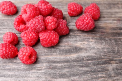 Photo of Tasty ripe raspberries on wooden table, closeup. Space for text