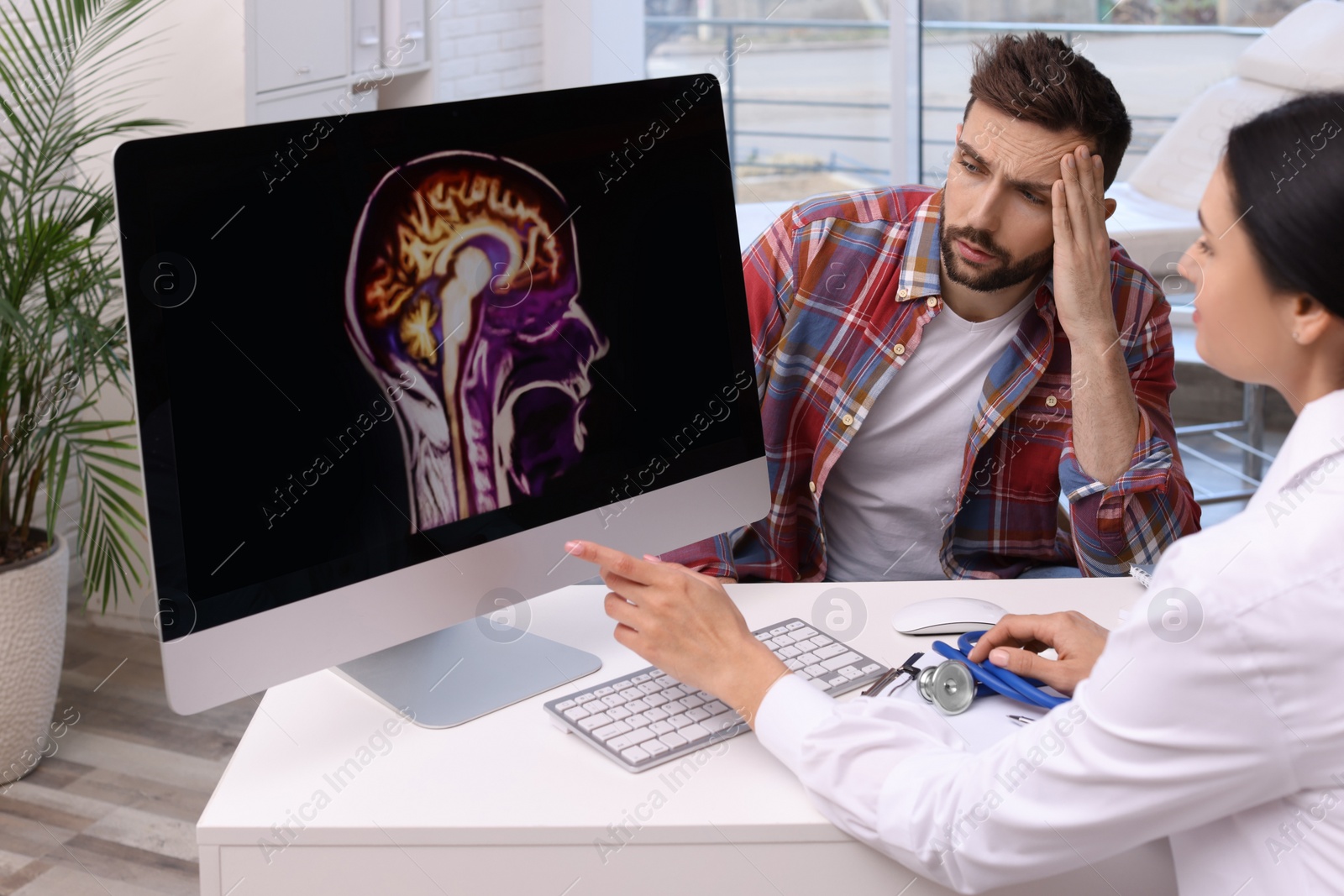 Photo of Neurologist showing brain scan to sad man in clinic