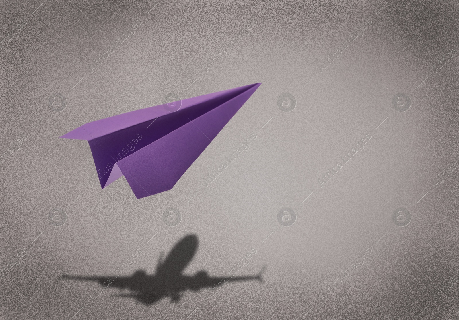 Image of Flying paper plane and shadow of a real airplane on grey background