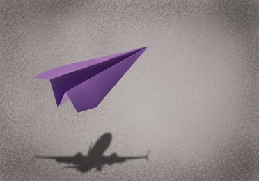 Flying paper plane and shadow of a real airplane on grey background