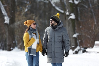 Photo of Happy young couple walking in snowy park on winter day
