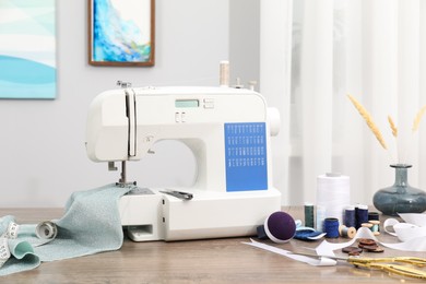 Photo of White sewing machine, cloth and craft accessories on wooden table indoors