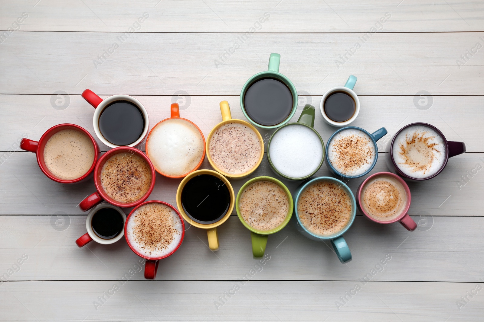 Photo of Many different cups with aromatic hot coffee on white wooden table, flat lay