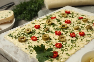 Photo of Fresh butter board with cut olives, dill and pepper on grey table, closeup