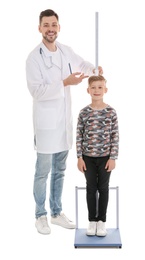 Photo of Doctor measuring little boy's height on white background