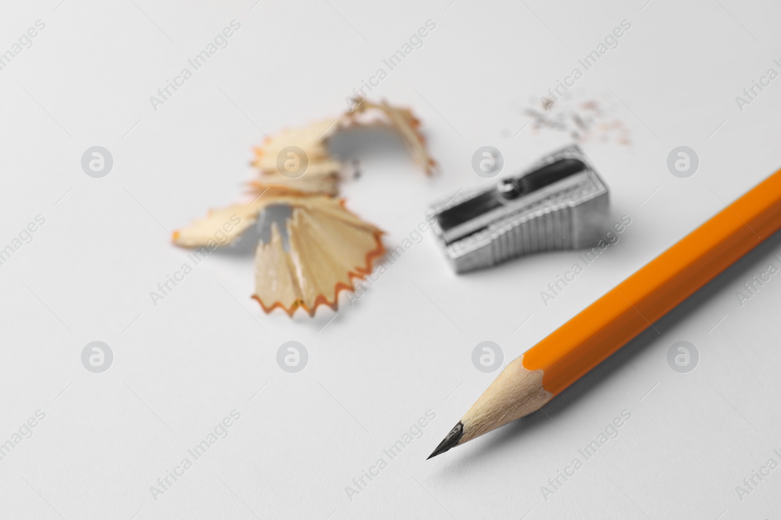 Photo of Graphite pencil, shavings and sharpener on white background, closeup