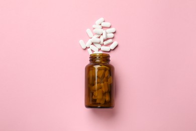 Photo of Bottle and vitamin capsules on pink background, top view