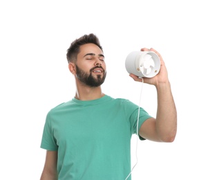 Photo of Man enjoying air flow from portable fan on white background. Summer heat