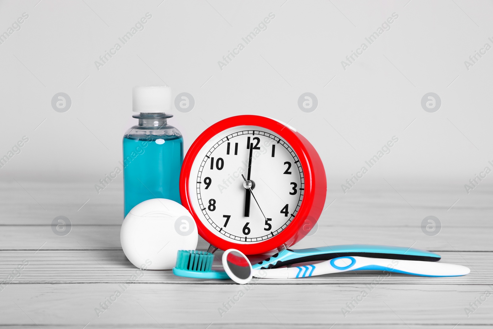 Photo of Composition with dental floss, alarm clock and different teeth care products on white wooden table