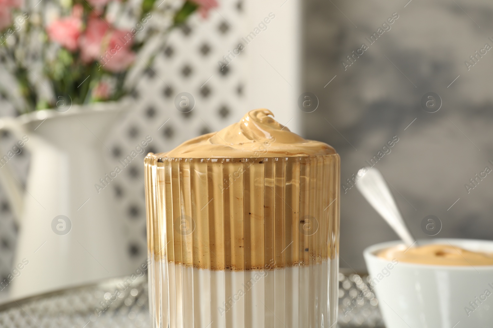Photo of Glass of delicious dalgona coffee against blurred background, closeup