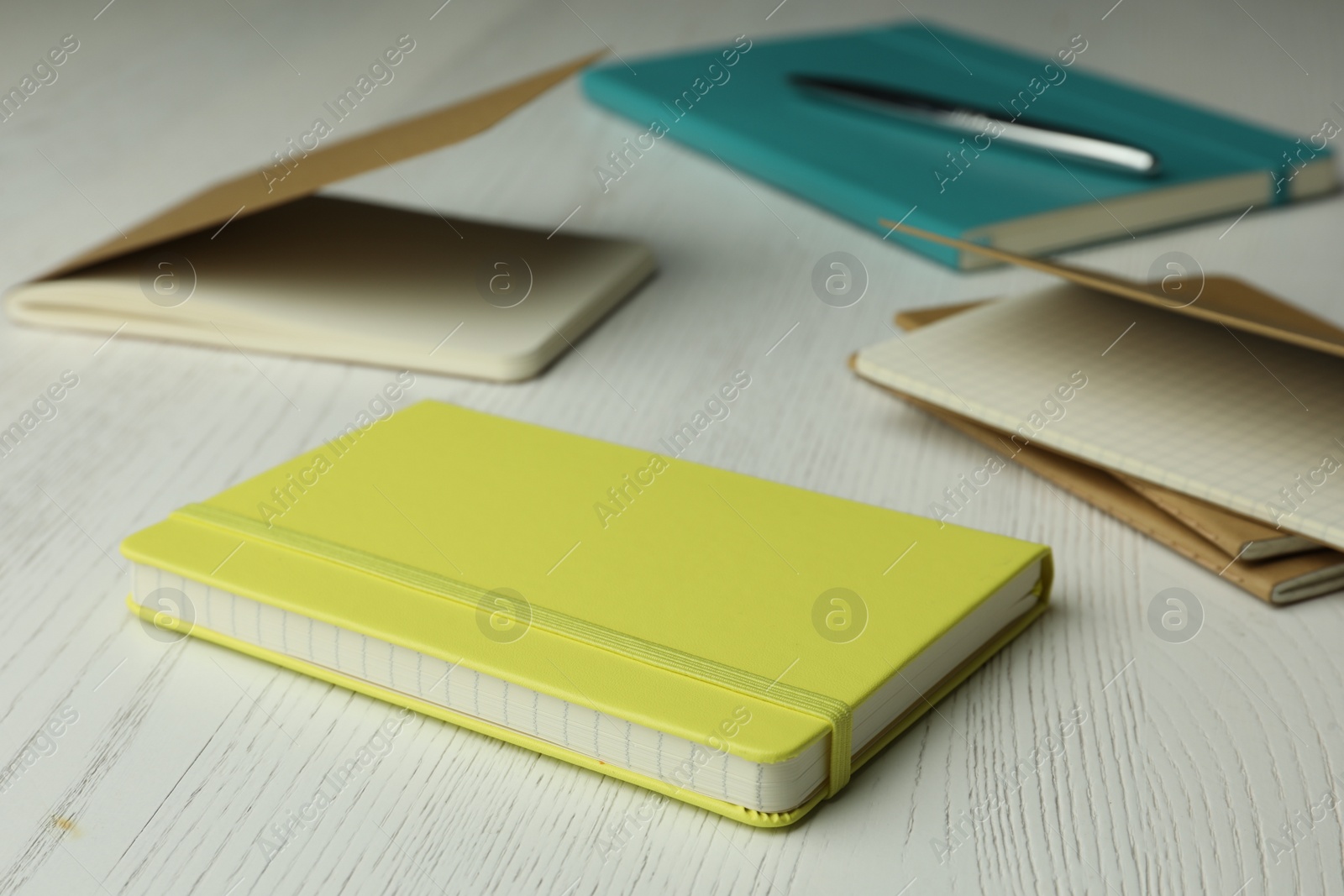Photo of Yellow planner and notebooks on white wooden table