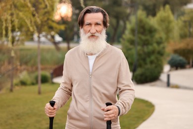 Photo of Senior man with Nordic walking poles outdoors