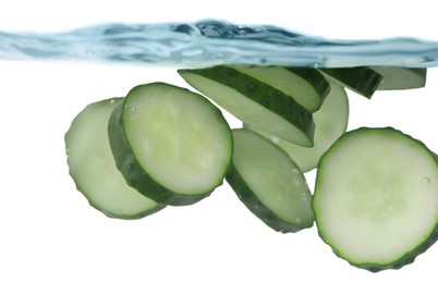 Photo of Slices of fresh cucumber in glass with water on white background, closeup