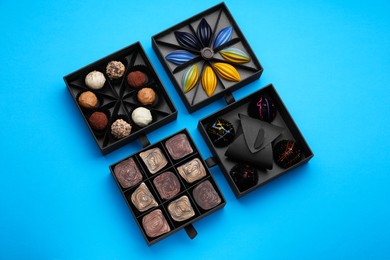 Boxes of tasty chocolate candies on blue background, flat lay