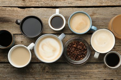 Photo of Different coffee drinks in cups and beans on wooden table, flat lay