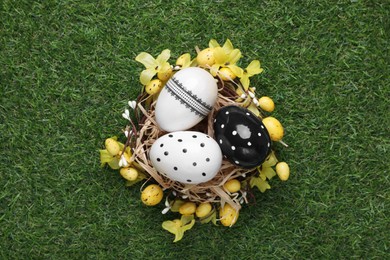 Festively decorated Easter eggs on green grass, top view