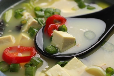 Photo of Bowl of delicious miso soup with tofu and spoon, closeup