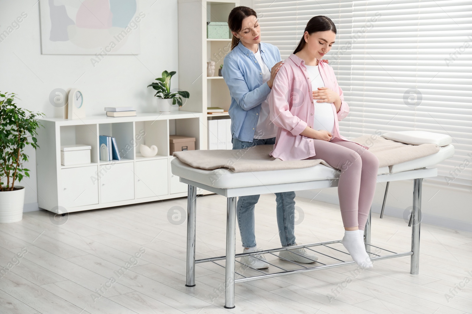 Photo of Doula taking care of pregnant woman indoors. Preparation for child birth