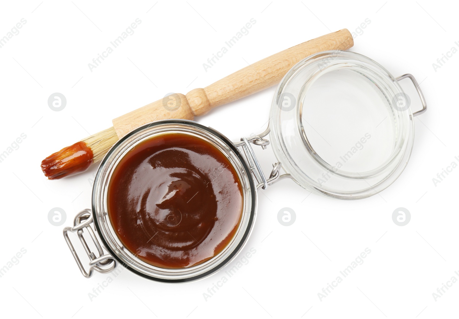Photo of Tasty barbecue sauce in glass jar and brush isolated on white, top view
